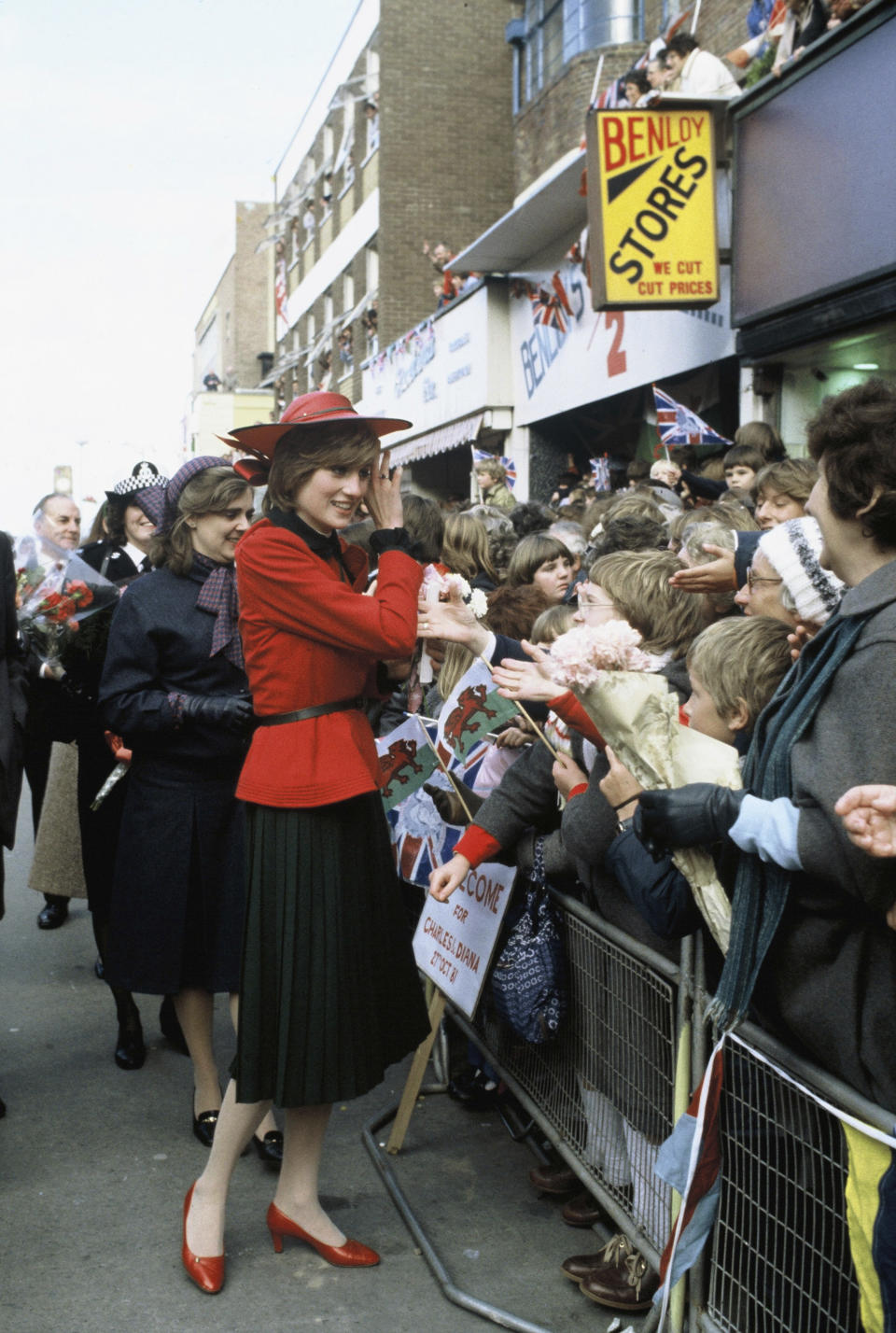 RHYL, WALES - OCTOBER 27: Diana, Princess of Wales, wearing a red suit with a black pleated skirt designed by Donald Campbell and a hat designed by John Boyd, is greeted by well-wishers during a walkabout on October 27, 1981 in Rhyl, United Kingdom. (Photo by Anwar Hussein/Getty Images)