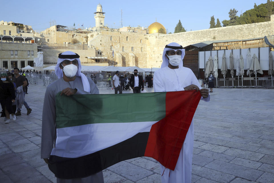 Emirati singer Walid Aljasim, left, and an unidentified companion pose for a photo with the flag of the United Arab Emirates during their visit in Jerusalem, next to the Western Wall the holiest site where Jews can pray, Thursday, Dec. 3, 2020. (AP Photo/Mahmoud Illean)