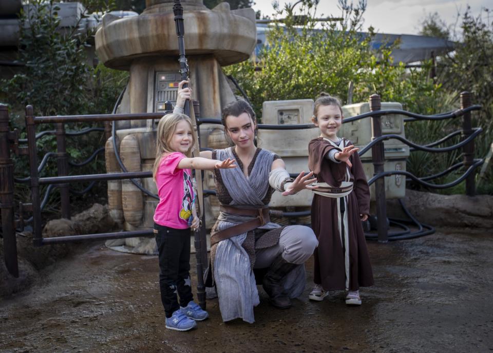 A cast member dressed as Rey with two girls