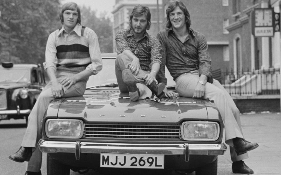 Chelsea FC footballers Bill Garner, Alan Hudson and Micky Droy sitting on a new Ford Capri in London, in 1972 - Evening Standard/Hulton Archive