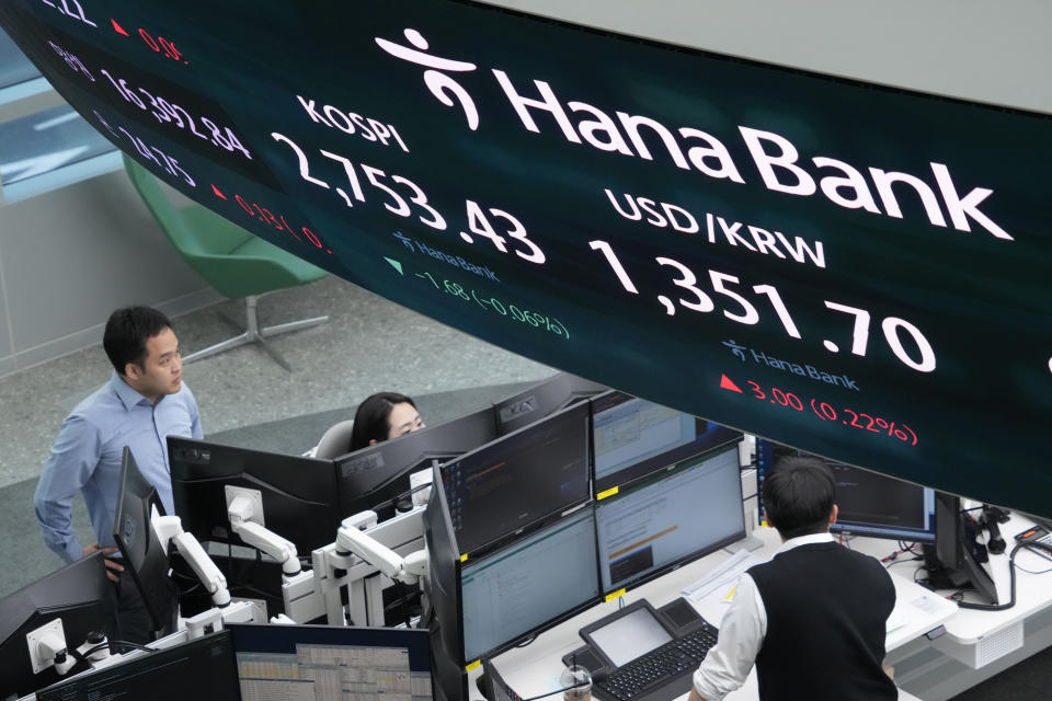 Currency traders work near the screens showing the Korea Composite Stock Price Index (KOSPI) and the foreign exchange rate between U.S. dollar and South Korean won, top right, at the foreign exchange dealing room of the KEB Hana Bank headquarters in Seoul, South Korea, Thursday, March 28, 2024. Asian shares were mixed on Thursday after U.S. stocks broke out of a three-day lull to close at a record. (AP Photo/Ahn Young-joon)