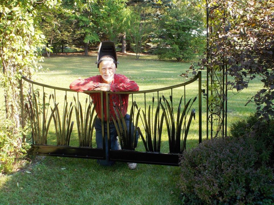 Frenchtown Township metal artist Greg Koesel is shown with a gated garden arbor he created.