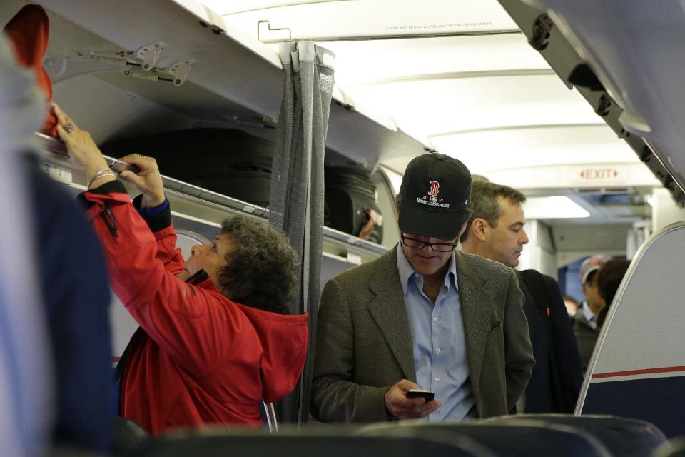 FILE - In this Thursday, Oct. 31, 201 file photo, a passenger checks his cell phone while boarding a flight, in Boston. The Federal Communications Commission might be ready to permit cellphone calls in flight. Old concerns about electronics being a danger to airplane navigation have been debunked. And carriers could make some extra cash charging passengers to call a loved one from 35,000 feet. But that extra money might not be worth the backlash from fliers who view overly-chatty neighbors as another inconvenience to go along with smaller seats and stuffed overhead bins. (AP Photo/Matt Slocum, File)