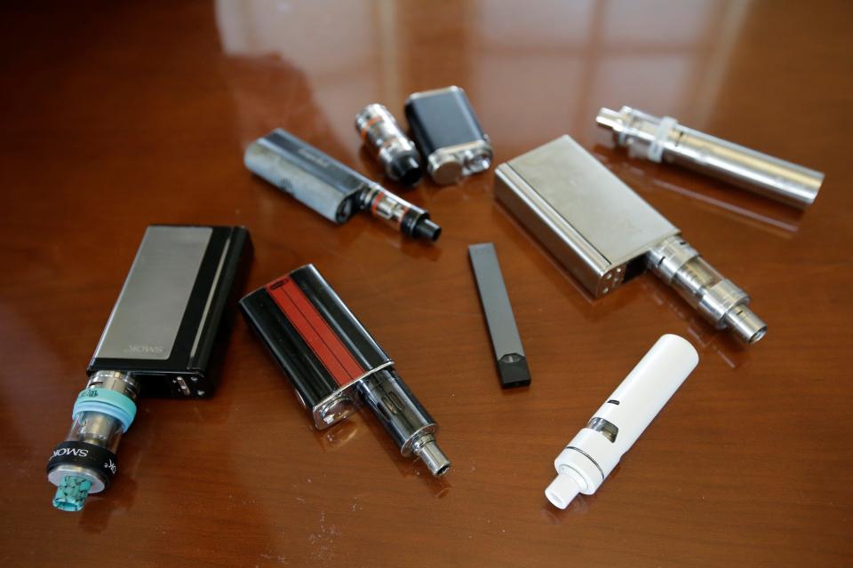 FILE - This Tuesday, April 10, 2018 file photo shows vaping devices, including a Juul, center, that were confiscated from students at a high school in Marshfield, Mass. (AP Photo/Steven Senne, File) ORG XMIT: MASR201