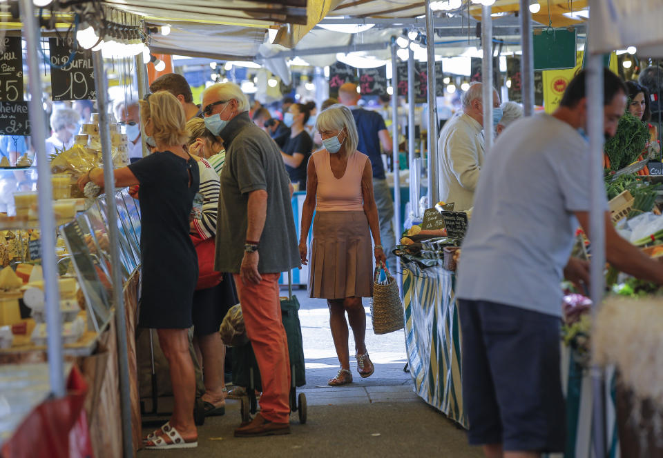 People wearing protective face masks as precaution against the conoravirus shop at a outdoor market in Versailles, west of Paris, Friday, Sept. 11, 2020. France has seen a sharp uptick in new Covid cases in recent weeks. (AP Photo/Michel Euler)