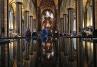 People are reflected in the 'Refection Pool' inside Salisbury Cathedral in Salisbury, England, Wednesday, Jan. 20, 2021, as they leave after receiving their Pfizer-BioNTech vaccination. Salisbury Cathedral opened its doors for the second time as a venue for the Sarum South Primary Care Network COVID-19 Local Vaccination Service. (AP Photo/Frank Augstein)