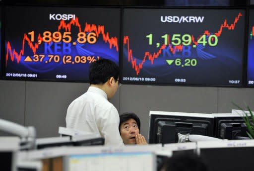 Currency dealers talk in front of screens showing South Korea's benchmark stock index (L) and the Korean won/USD exchange rate (R) in a dealing room at the Korea Exchange Bank in Seoul on June 18, 2012. Asian markets surged Monday and the euro rose after Greek pro-austerity parties won enough votes to form a government, but optimism it will stay was tempered with warnings the future is uncertain