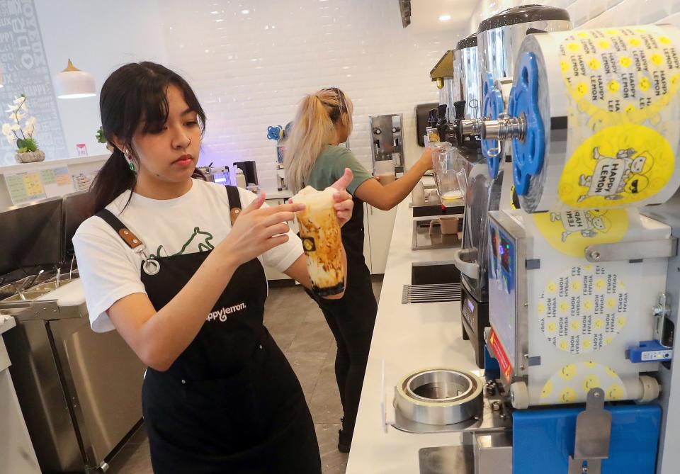 Mia Tatekawa carries a prepared brown sugar milk tea with boba to the sealer machine at Happy Lemon in Silverdale on Monday, Aug. 7, 2023.