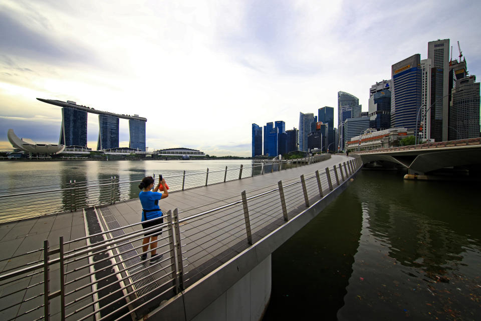 SINGAPORE - NOVEMBER 24: A woman wearing protective mask takes a photo of the city skyline at Marina Bay on November 24, 2020 in Singapore. As of November 23, the Ministry of Health confirmed five new imported COVID-19 cases bringing the country's total to 58,165. For the 13th straight day, there are no new cases of locally transmitted infection. (Photo by Suhaimi Abdullah/Getty Images)