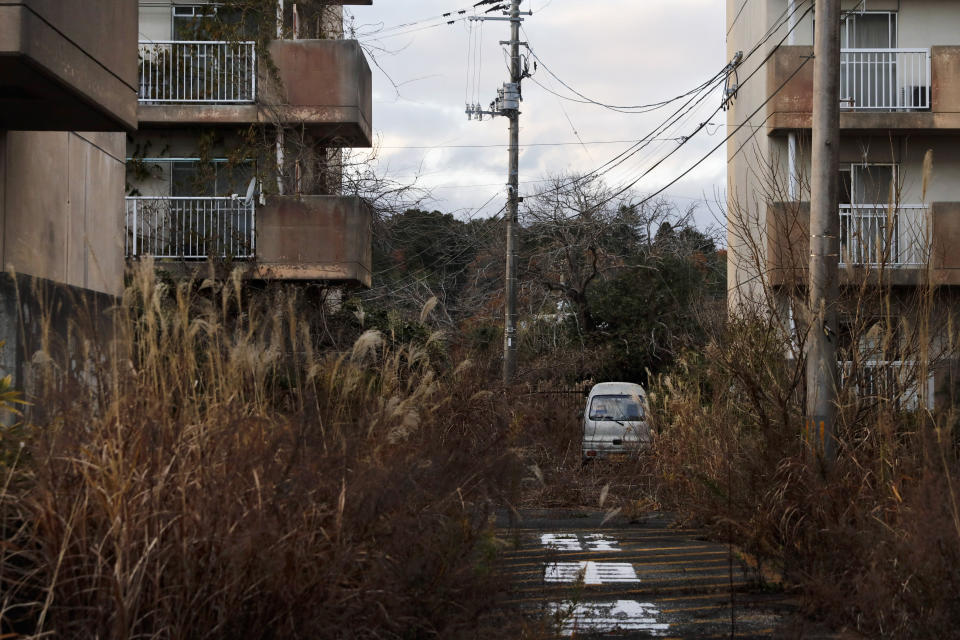 FILE - In this Dec. 3, 2019, file photo, weeds grow in an abandoned apartment complex, in Futaba, Fukushima prefecture, Japan. Japan’s government partially lifted Wednesday, March 4, 2020, an entry ban for Futaba, the last town that remained off-limits since it was entirely forced to evacuate following the Fukushima nuclear disaster nine years ago, a symbolic move by the central government to showcase the region's recovery ahead of the Olympics. The partial opening, however, is only a 2.4 square-kilometer (less than 1 square-mile) area near the main Futaba train station, which will reopen later this month to reconnect it with the rest of the region for the first time since the accident. The vast majority of the town, however, still remains off-limits except for those who get permission for a day visit. (AP Photo/Jae C. Hong, File)