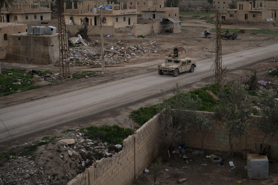 A Humvee drives in a village recently retaken from Islamic State militants by U.S.-backed Syrian Democratic Forces (SDF) near Baghouz, Syria, Sunday, Feb. 17, 2019. Islamic State militants are preventing more than 1,000 civilians from leaving a tiny area still held by the extremist group in a village in eastern Syria, a spokesman for the U.S.-backed Syrian militia fighting the group said Sunday. (AP Photo/Felipe Dana)