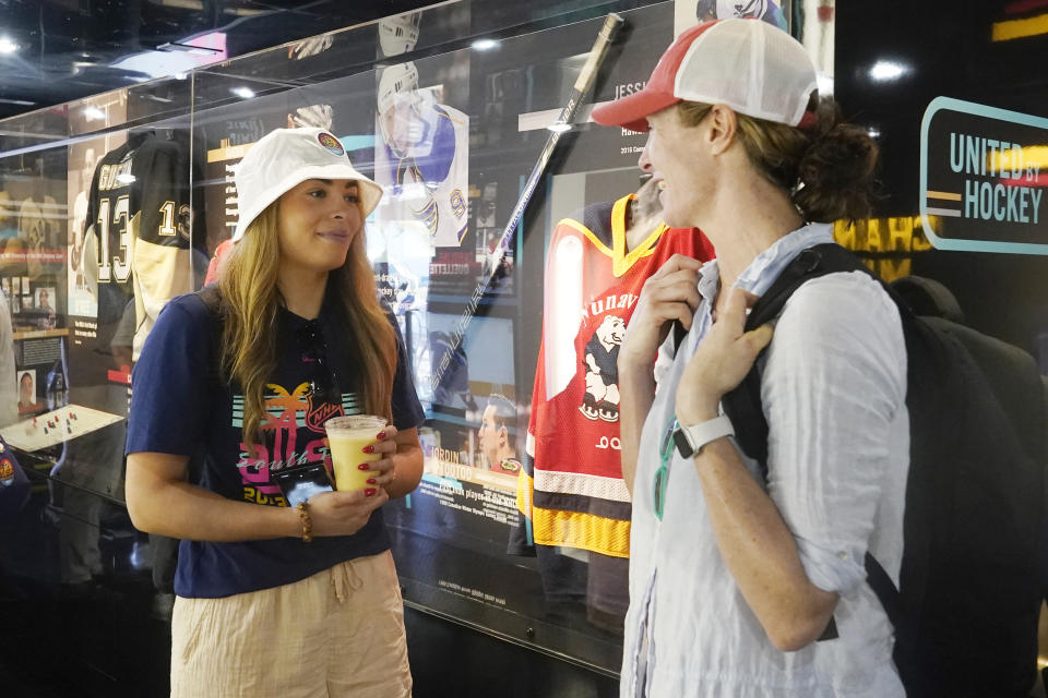 Sarah Nurse, left, a Canadian hockey player and two-time Olympic gold medalist, and A.J. Mleczko, right, a former U.S. hockey player and a 1998 Olympic gold medalist, speak while viewing the exhibits inside the United Hockey Mobile Museum, Thursday, Feb. 2, 2023, in Fort Lauderdale, Fla. (AP Photo/Marta Lavandier)