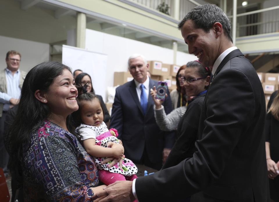 Venezuela's self-proclaimed interim president Juan Guaido visits with a Venezuelan migrant and her daughter, in Bogota, Colombia, Monday, Feb. 25, 2019. Guaido in his visit to the Colombian capital was afforded all the trappings of a head of state. He posed for selfies with well-wishers upon arriving for or an emergency summit of regional leaders and stood before a pile of aid boxes stamped with the U.S. flag as he and Vice President Pence greeted a group of Venezuelan migrants. (AP Photo/Martin Mejia)