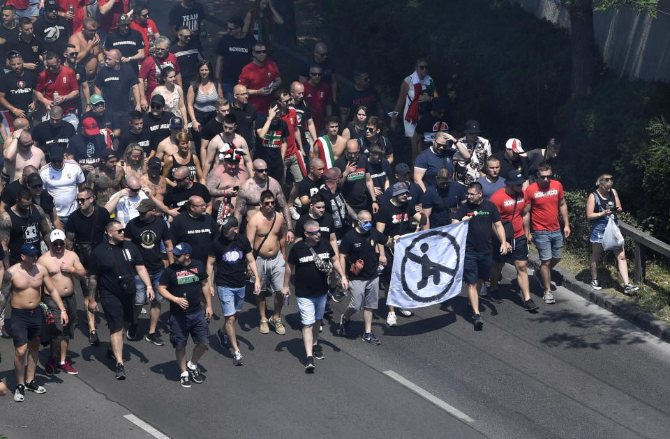 FILE - In this Saturday, June 19, 2021 file photo Hungarian fans, carrying a banner opposed to players taking the knee, march towards the Puskas Arena in Budapest, Hungary just hours before Hungary will face France in their Euro 2020 group F preliminary round soccer match. Populist Prime Minister Viktor Orban has long used soccer to advance his right-wing politics, and now widespread international criticism of a new Hungarian law that is seen as targeting the LGBT community has turned this month's Euro 2020 tournament into a major stage for his challenge to Europe's liberal values. (Zoltan Mathe/MTI via AP, File)