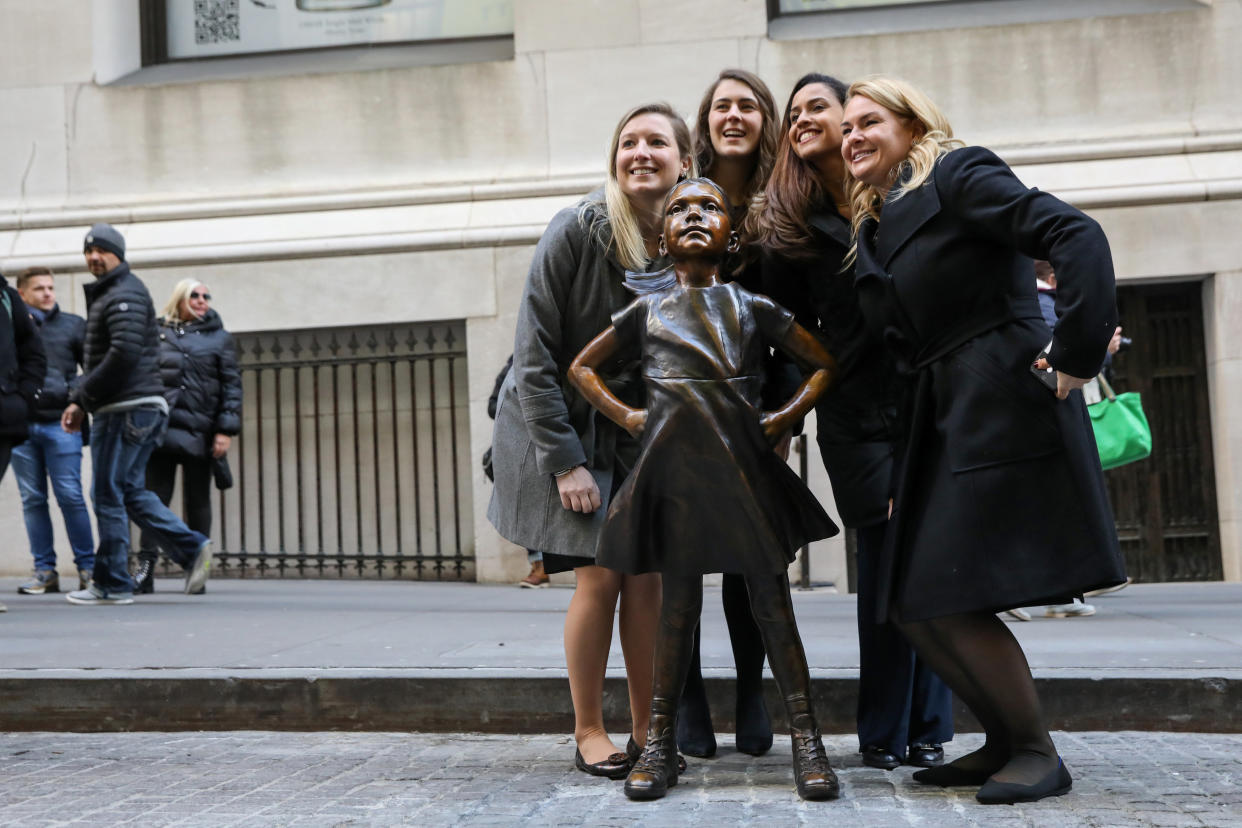 Women pose with the ‘Fearless Girl’ statue. Photo: Reuters