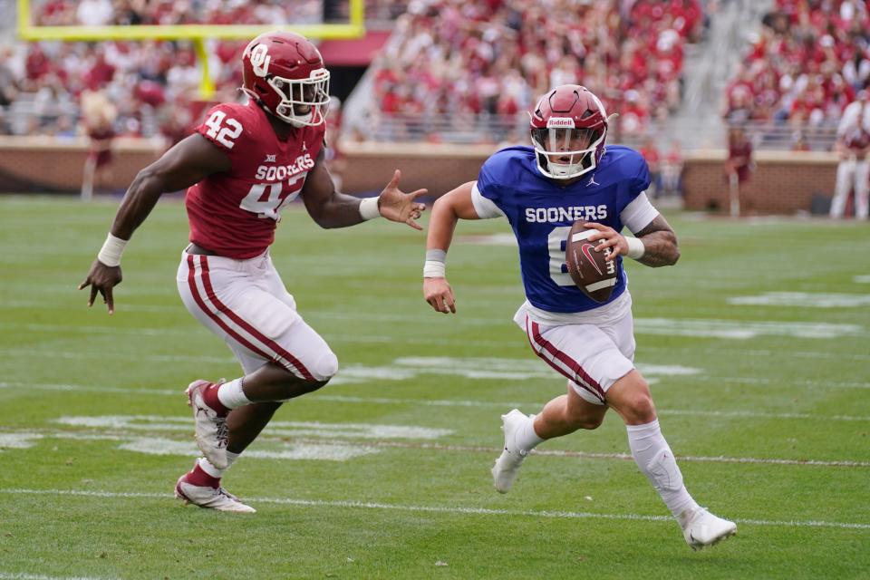 Oklahoma quarterback Dillon Gabriel (8) carries past Noah Arinze (42) during the school's NCAA college spring football game, Saturday, April 23, 2022, in Norman, Okla. (AP Photo/Sue Ogrocki)