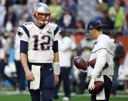 A ball boy holds footballs as New England Patriots quarterback Tom Brady (12) warms-up ahead of the start of the NFL Super Bowl XLIX football game against the Seattle Seahawks in Glendale, Arizona, February 1, 2015. REUTERS/Lucy Nicholson