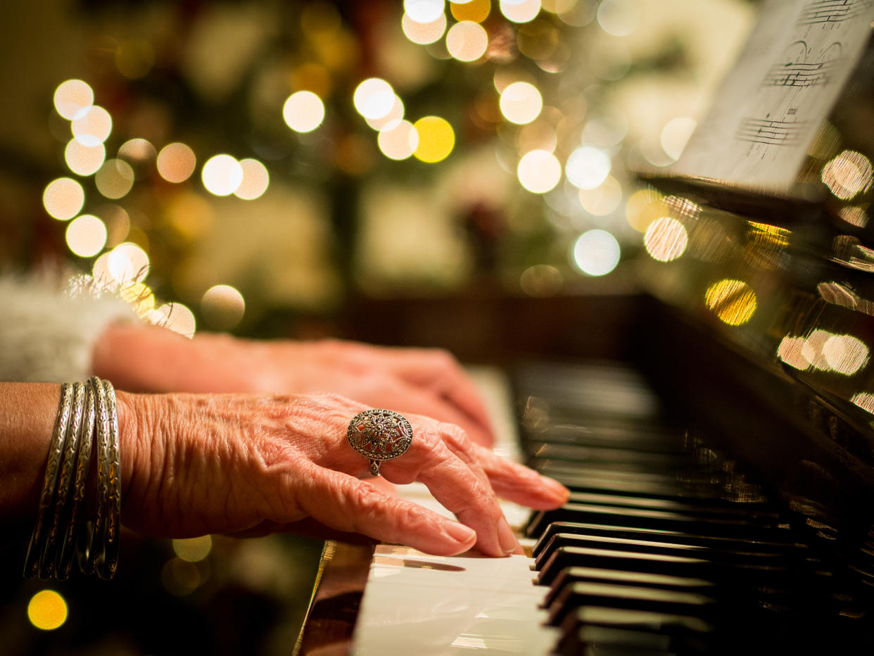 Close up of the hands of a woman playing Christmas carols on a piano