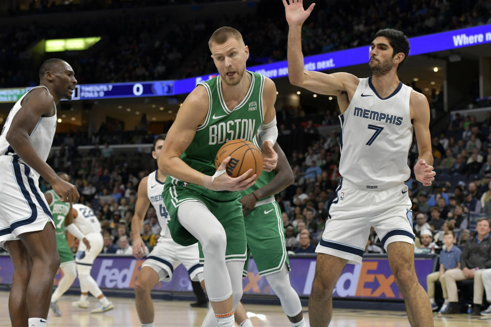 Boston Celtics center Kristaps Porzingis, center, handles the ball against Memphis Grizzlies forward Santi Aldama (7) in the first half of an NBA basketball game Sunday, Nov. 19, 2023, in Memphis, Tenn. (AP Photo/Brandon Dill)