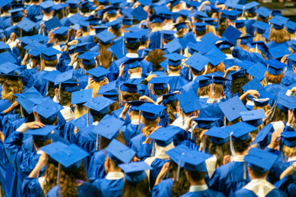 Student audience wearing grown and mortarboard hats during High School Graduation Ceremony