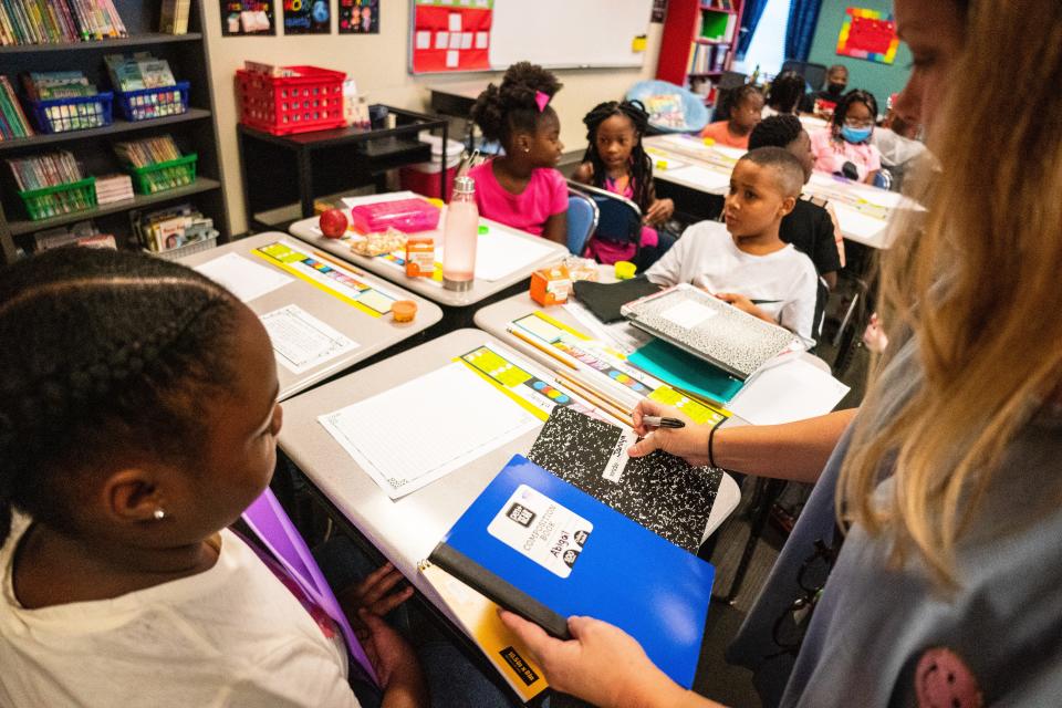 Fourth grade teacher Tracy Lindsey passes out labeled composition notebooks to her class at University Place Elementary School on the first day of the 2022-2023 school year on Aug. 10, 2022.