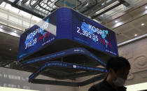 A man wearing a face mask walks near a screen showing the Korea Composite Stock Price Index (KOSPI) at the Korea Exchange in Seoul, South Korea, Thursday, Oct. 8, 2020. Asian shares were mostly higher Thursday on optimism that U.S. stimulus may be coming, as President Donald Trump appeared to reverse his earlier decision to halt talks on another economic rescue effort. (AP Photo/Lee Jin-man)