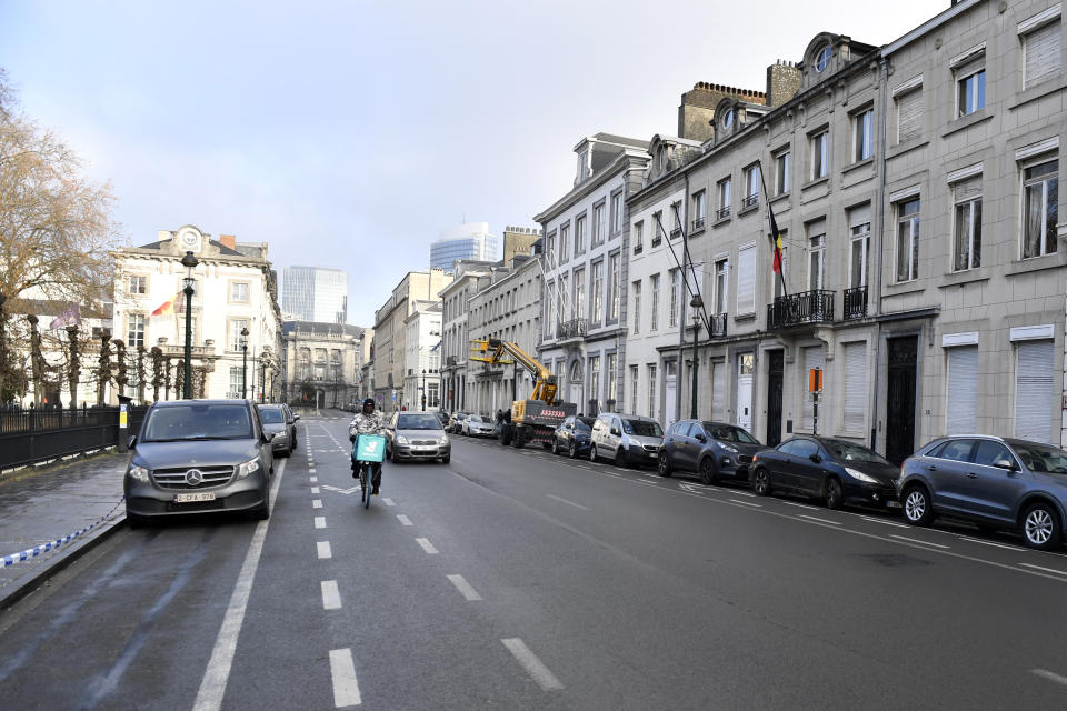 A car and bicycle pass by the office of Belgian NGO 'No Peace without Justice' in Brussels, Friday, Dec. 16, 2022. No one answers the door buzzer at the offices of the two campaign groups linked to a cash-for-influence corruption scandal at the European Union's parliament, allegedly involving Qatari officials. No obvious light shines on what goes on inside their premises. (AP Photo/Geert Vanden Wijngaert)