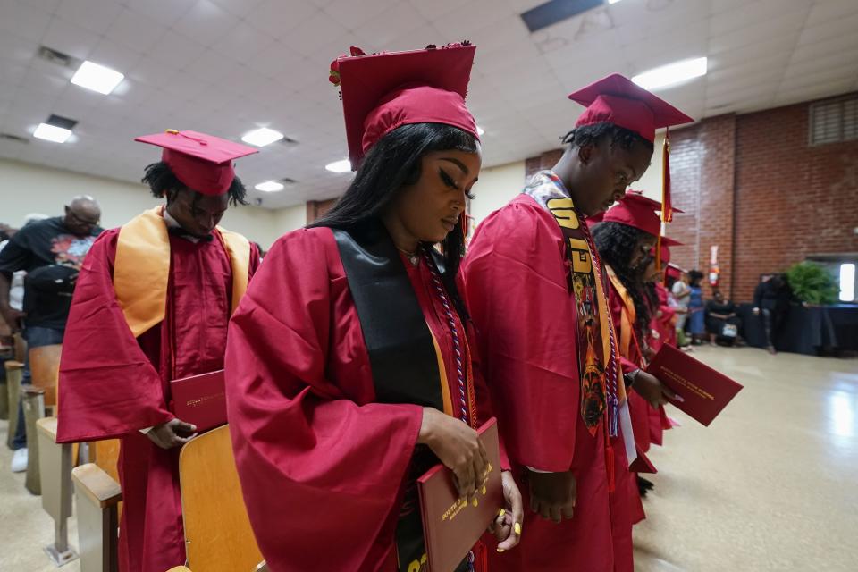 Members of the graduating class of South Delta High School bow their heads during their commencement, at the South Delta Middle School in Anguilla, Miss., Friday, May 19, 2023. Many students living in nearby Rolling Fork had their homes destroyed in a recent tornado. (AP Photo/Gerald Herbert)