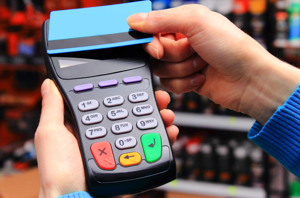 Hand of woman paying with contactless credit card with NFC technology in shop, cashless paying for shopping or products concept (Hand of woman paying with contactless credit card with NFC technology in shop, cashless paying for shopping or products co