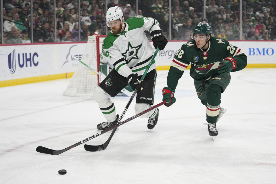 Dallas Stars defenseman Jani Hakanpää (2) and Minnesota Wild center Connor Dewar (26) battle for the puck during the first period of an NHL hockey game Thursday, Dec. 29, 2022, in St. Paul, Minn. (AP Photo/Abbie Parr)