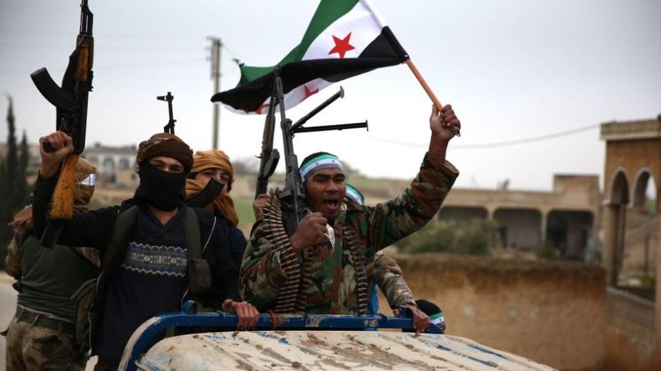 Turkish-backed Syrian rebel fighters raise the opposition's flag as they arrive in the border town of Qirata (25 December 2018)