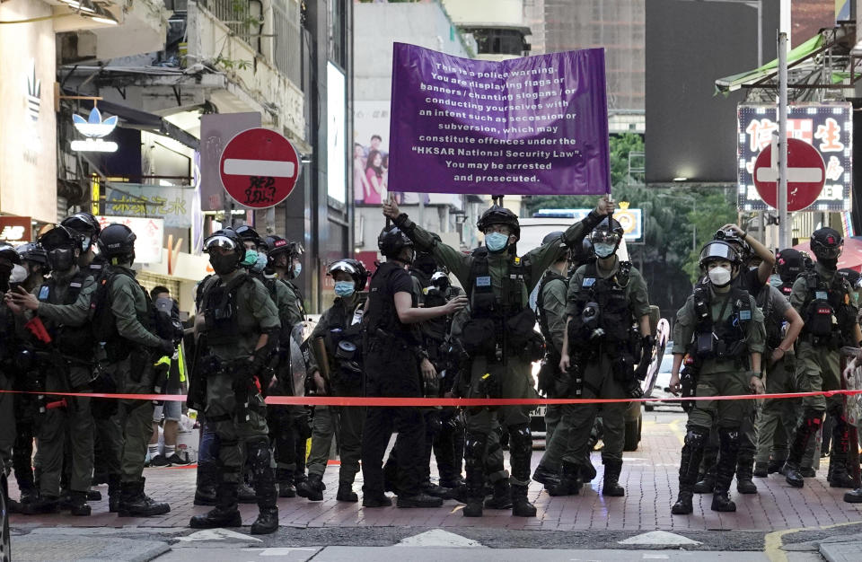 Police officers raise a warning banner at a downtown street in Hong Kong Sunday, Sept. 6, 2020. About 30 people were arrested Sunday at protests against the government's decision to postpone elections for Hong Kong's legislature, police and a news report said. (AP Photo/Vincent Yu)