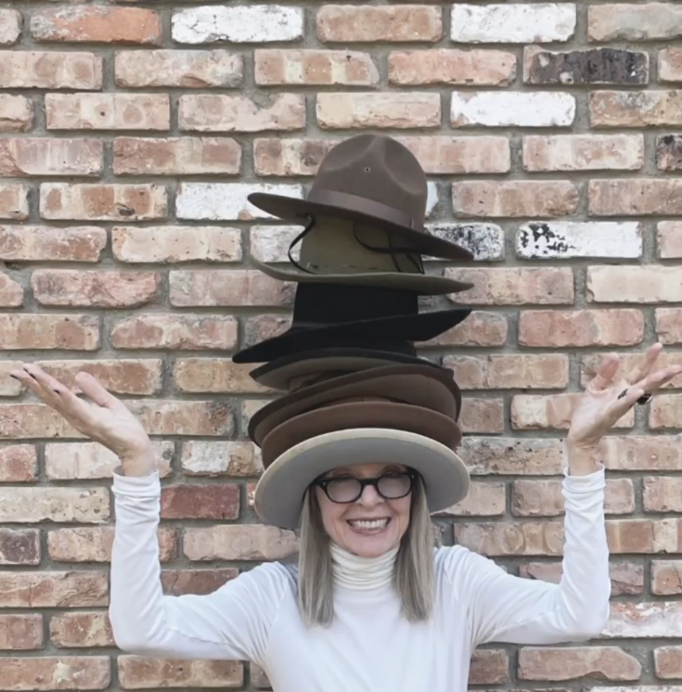 Diane wearing a stack of wide-brimmed hats