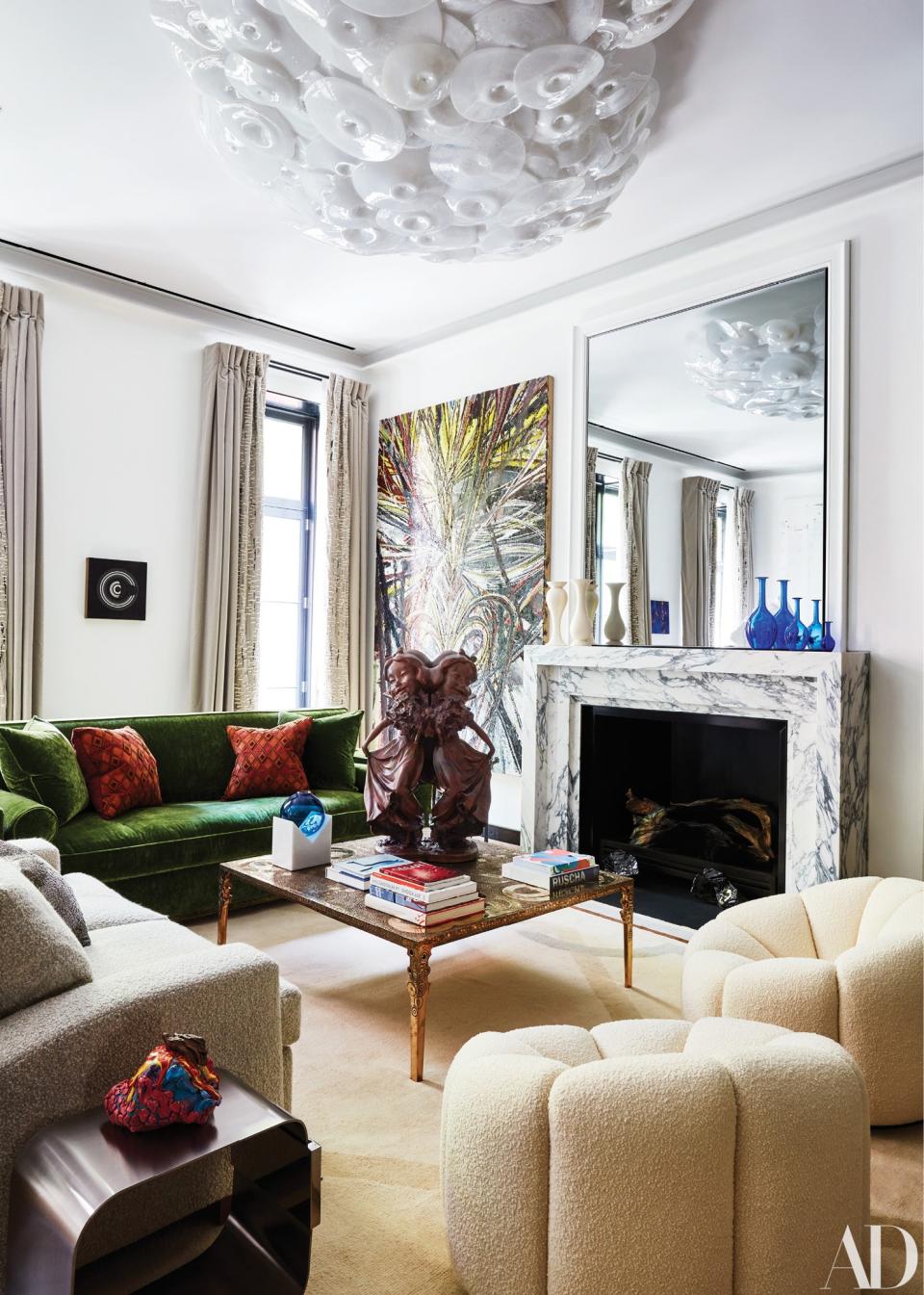 The art-filled living room is decorated with custom sofas and a pair of Pierre Paulin chairs. A Paul McCarthy sculpture sits atop a cocktail table by Ingrid Donat; Maria Pergay side table.