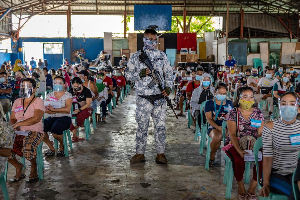 A soldier stands guard as residents out of work due to the coronavirus pandemic queue for ($20) cash aid on April 7,2021 in Manila, Philippines.