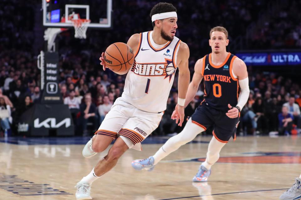 Phoenix Suns guard Devin Booker (1) drives past New York Knicks guard Donte DiVincenzo (0) in the second quarter at Madison Square Garden on Nov. 26, 2023.