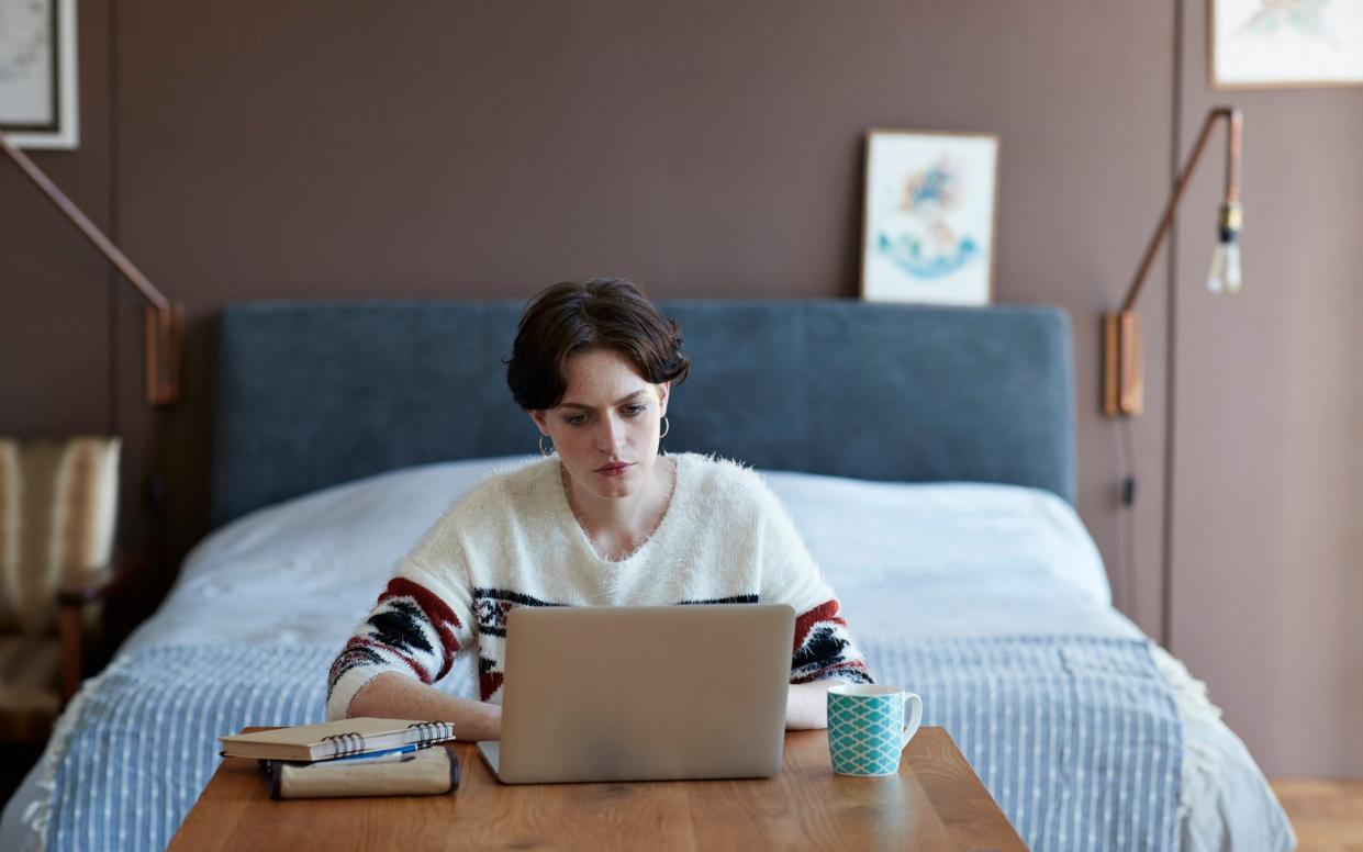 Young woman in her bedroom working at her desk on investments