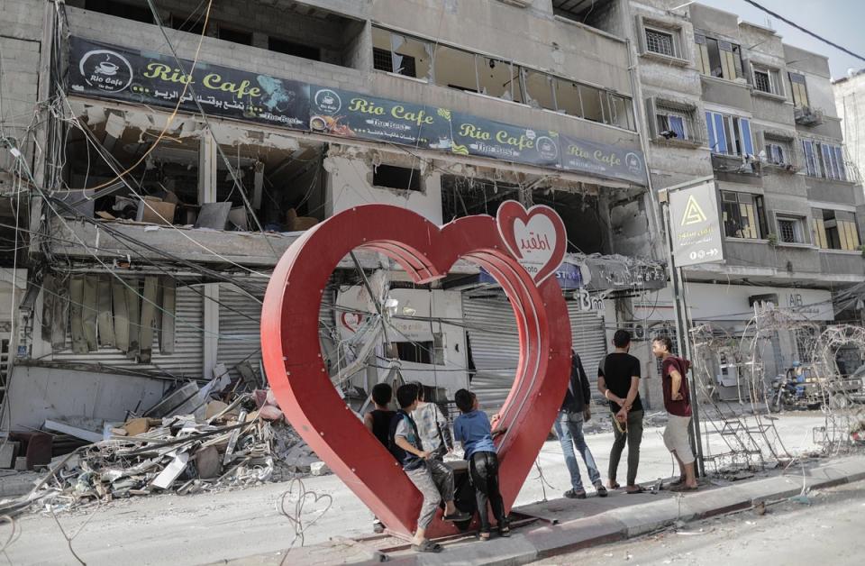 Palestinian youths stand on a heart-shaped installation next to the rubble of a building following an Israeli airstrike on Khan Younis refugee camp, southern Gaza Strip, on Sunday (EPA)