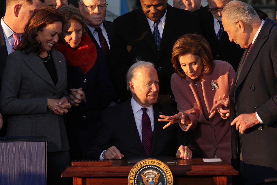 WASHINGTON, DC - NOVEMBER 15: U.S. President Joe Biden (3rd-R) talks to Speaker of the House Rep. Nancy Pelosi (D-CA) (2nd-R) as Senate Majority Leader Sen. Chuck Schumer (D-NY) (R) and Vice President Kamala Harris (L) look on after signing the Infrastructure Investment and Jobs Act as he is surrounded by lawmakers and members of his Cabinet during a ceremony on the South Lawn at the White House on November 15, 2021 in Washington, DC. The $1.2 trillion package will provide funds for public infrastructure projects including improvements to the country’s transportation networks, increasing rural broadband access, and projects to modernize water and energy systems. (Photo by Alex Wong/Getty Images)