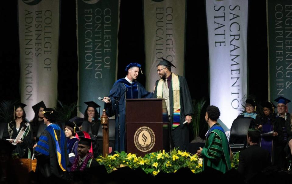 A Sacramento State faculty member confiscates the microphone from a graduating student who had seized it after an unscripted trip to the podium during the Sacramento State commencement ceremony at Golden 1 Center on Friday. The graduate walked off the stage without incident.