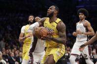 Los Angeles Lakers' LeBron James, center, drives past Brooklyn Nets' Kyrie Irving during the first half of an NBA basketball game Thursday, Jan. 23, 2020, in New York. (AP Photo/Frank Franklin II)