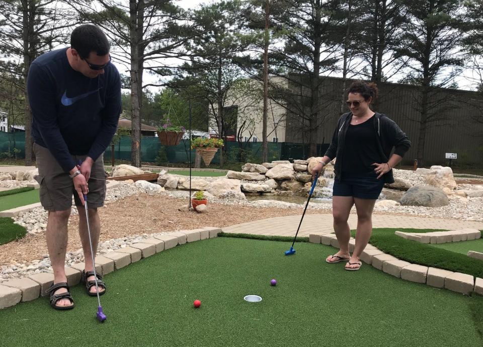 Jerry Koss of Oregon, Wis., putts out on the 18th hole as Emily Koss watches at Evergreen Miniature Golf, a new eco-themed mini golf course in Fish Creek.