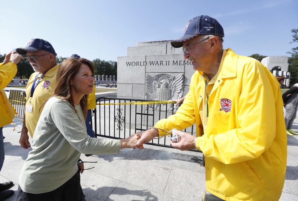 U.S. Representative Michele Bachmann (R-MN) (L) greets World War Two veterans at the World War Two Memorial in Washington October 1, 2013. Despite the U.S. government shutdown affecting the site, a barricade was removed to give veterans access to the memorial. Up to one million federal workers were thrown temporarily out of work on Tuesday as the U.S. government partially shut down for the first time in 17 years in a standoff between President Barack Obama and congressional Republicans over healthcare reforms. REUTERS/Kevin Lamarque (UNITED STATES - Tags: POLITICS BUSINESS)