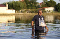 A man walks into floodwaters to deliver medicines to a relative after the country's rainstorm record, in the town of Palamas, near Karditsa, Thessaly region, central Greece, Friday, Sept. 8, 2023. Rescue crews in helicopters and boats are plucking people from houses in central Greece inundated by tons of water and mud after severe rainstorms caused widespread flooding. (AP Photo/Vaggelis Kousioras)