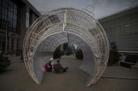 A man and two small children have a picnic inside of a giant holiday ornament outside EU headquarters in Brussels, Saturday, Dec. 19, 2020. The European Union and the United Kingdom were starting a "last attempt" to clinch a post-Brexit trade deal, with EU fishing rights in British waters the most notable remaining obstacle to avoid a chaotic and costly changeover on New Year. (AP Photo/Virginia Mayo)