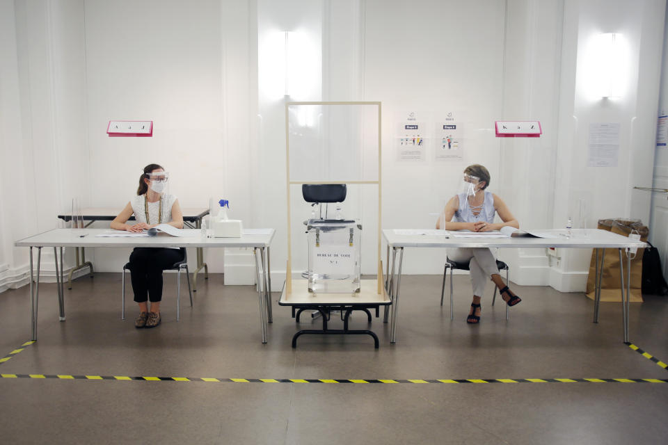 People wearing face mask and visor to protect against coronavirus sit behind a glass shield during a rehearsal of the vote for the local elections scheduled for Sunday, June 28, in Paris, Friday, June 26, 2020. France is to hold its Covid-19 delayed second round of local elections on June 28. (AP Photo/Thibault Camus)