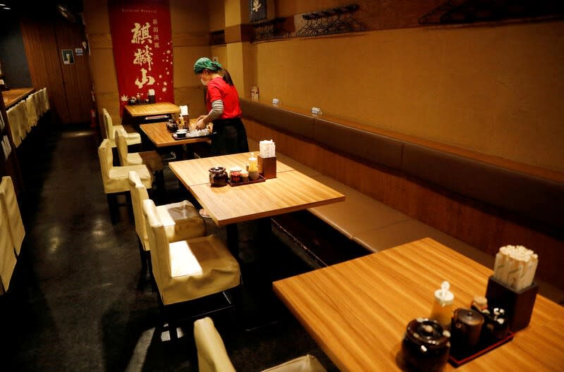 FILE PHOTO: A waitress wearing a protective mask cleans a table at Toshirhin restaurant in Tokyo