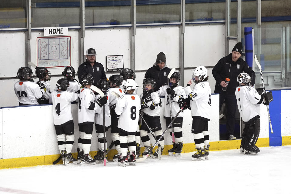 FILE - Minneapolis coach Colin Mueller, back right, stands with his team during a 10-and-under youth hockey game against Orono, Feb. 4, 2024, in Minneapolis. While Canada has seen a steep decline in children playing hockey in the sport's birthplace, the United States has experienced steady growth in that department over the past decade. (AP Photo/Abbie Parr, File)