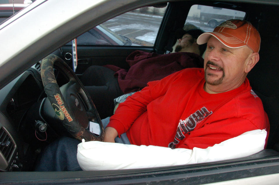 This Feb. 29, 2012 photo shows Gary Hancock of Magee, Miss. leaning against a pillow in his Chevrolet pickup as Richard Rayborn sleeps in the passenger seat while the pair wait to start work in the Bakken oil fields of eastern Montana, in Sidney, Mont. More than 16 million barrels of crude are now being pumped every month from the massive Bakken oil field beneath eastern Montana. But Sidney's new-found prosperity doesn't dull the sting of the recent kidnapping and apparent murder of a local teacher, Sherry Arnold, who authorities allege was snatched from a Sidney street by two men in search of their own slice of the boom's multi-billion-dollar payoff. (AP Photo/Matthew Brown)