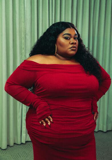 Da'Vine Joy Randolph poses in a red gown with her hands near her hips